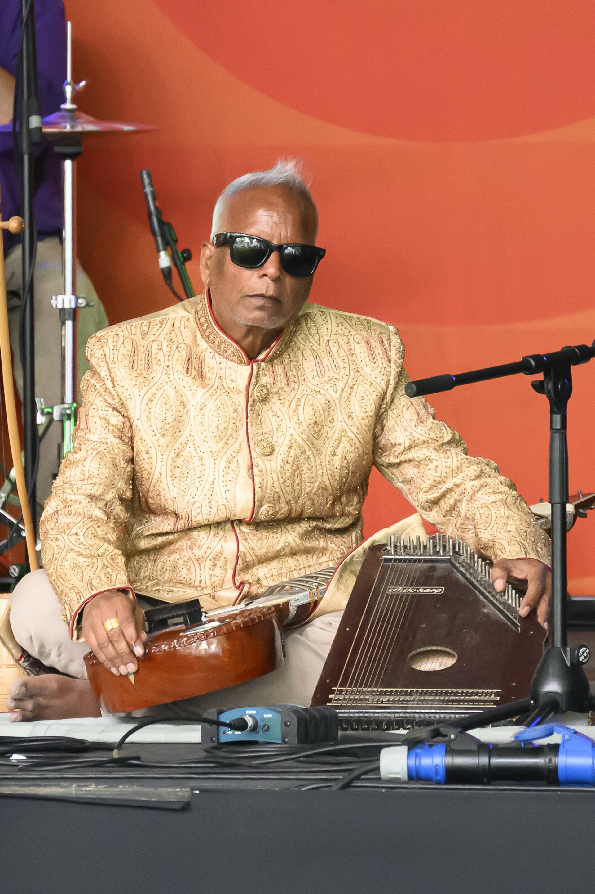 Baluji Shrivastav sitting on the stage prior to performing on the Free Stage at Cheltenham Jazz Festival in May 2025