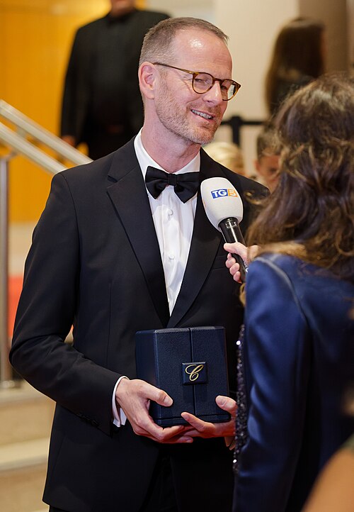 Joachim Trier being interviewed by press after winning an award at the 2025 Cannes Film Festival.