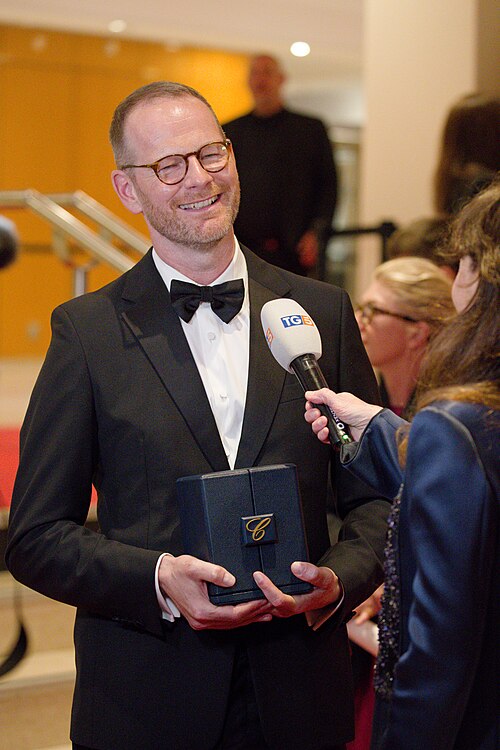 Joachim Trier being interviewed by press after winning an award at the 2025 Cannes Film Festival.
