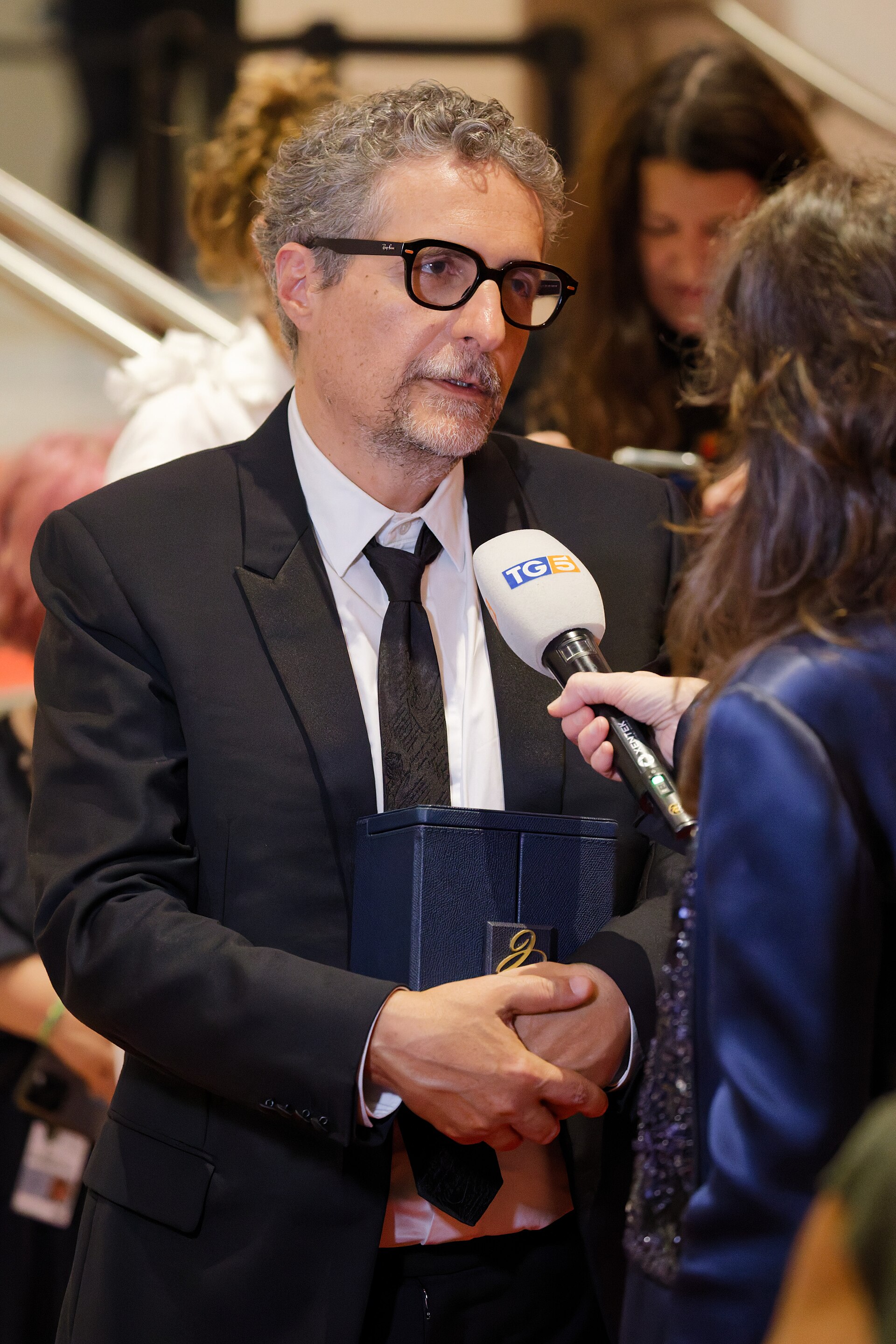 Kleber Mendonça Filho being interviewed by press after winning an award at the 2025 Cannes Film Festival.