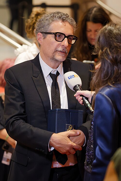 Kleber Mendonça Filho being interviewed by press after winning an award at the 2025 Cannes Film Festival.