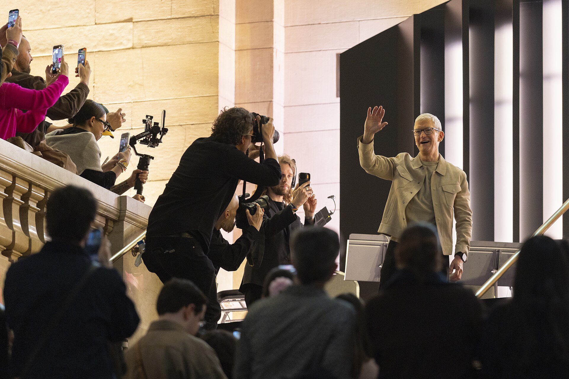 Tim Cook waves to attendees during Apple’s 50th-anniversary kickoff event at Apple’s Grand Central Terminal store in New York City on March 13, 2026. Spectators record and photograph Cook.