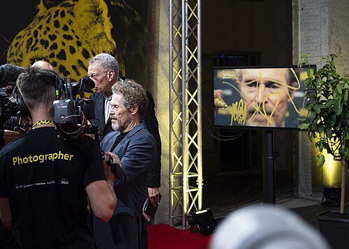Actor Willem Dafoe signing lens at 78th Locarno Film Festival red carpet for The Birthday Party