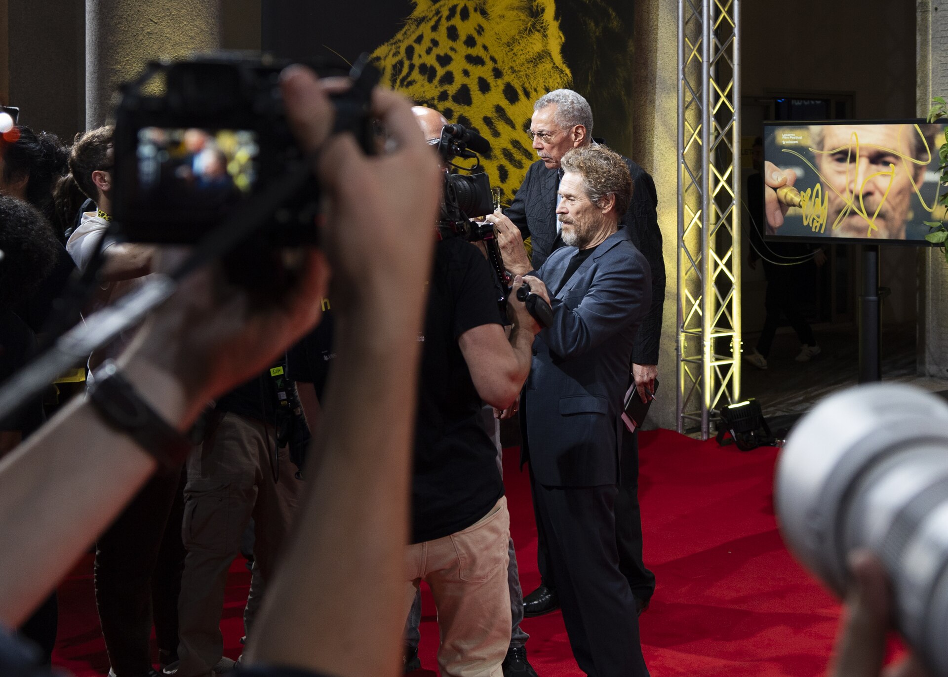 Actor Willem Dafoe signing lens at 78th Locarno Film Festival red carpet for The Birthday Party