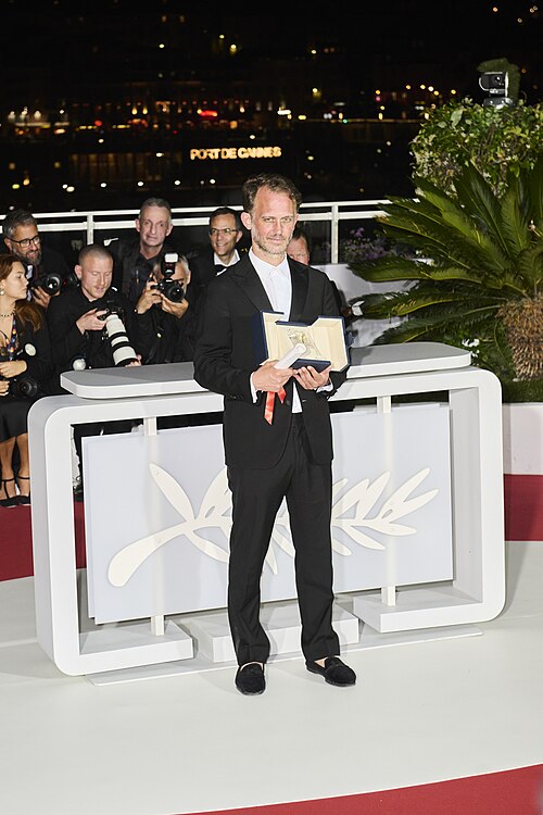 Emmanuel Marre stands with the Prix Du Scénario award at the 79th Cannes Film Festival